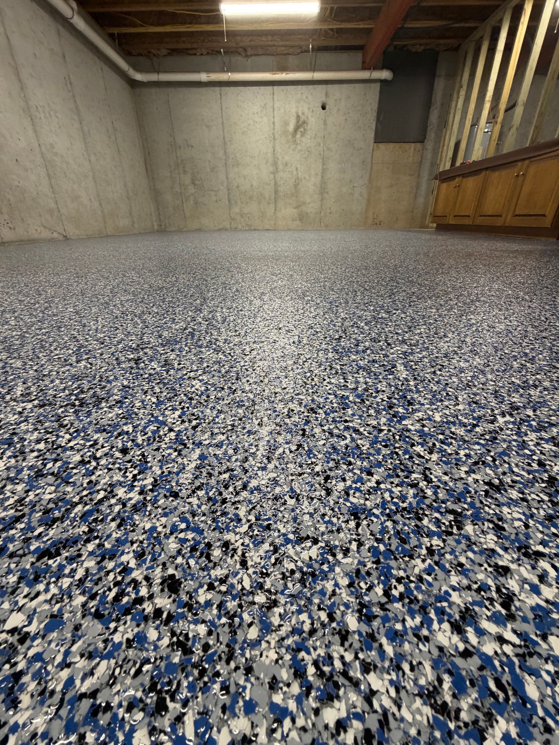 Blue, black and gray flake floor filling a poured-wall basement